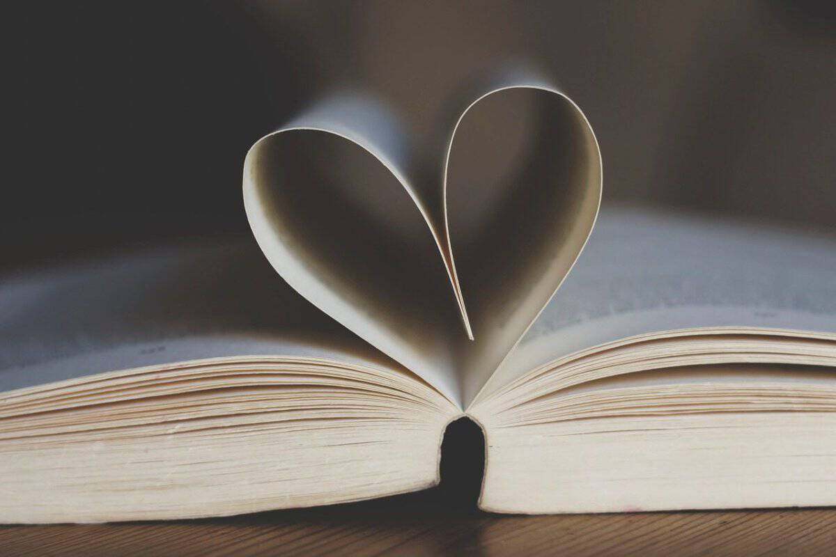 An open book, with the top pages bent into a heart shape